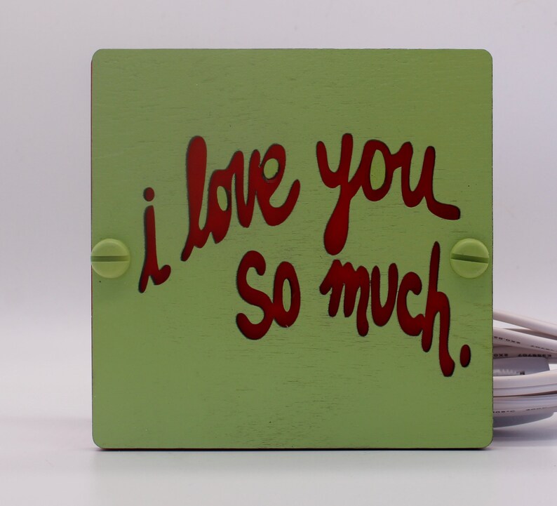 May include: A green wooden sign with the words "i love you so much" written in red.