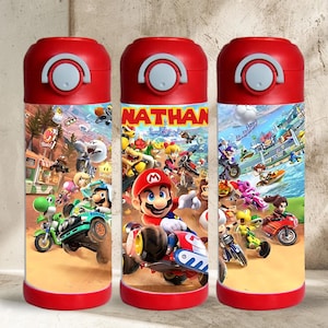 May include: Three cylindrical water bottles with red caps and bases, featuring a colorful graphic wrap of Mario Kart characters. The center bottle displays the name NATHAN in bold yellow letters above Mario driving a red kart on a dirt track.
