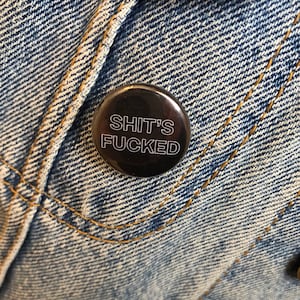 Sh*t’s F*cked 25mm black and white pinback badge