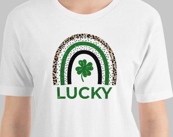 May include: White t-shirt with a green four-leaf clover in a black and brown leopard print rainbow with the word "LUCKY" underneath.