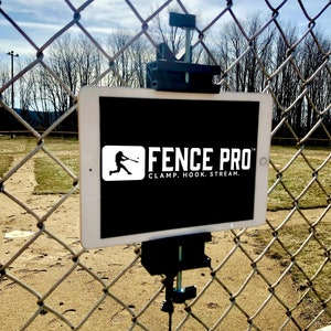 May include: A black metal clamp with a tablet attached to it. The tablet is displaying the text "FENCE PRO" with the tagline "CLAMP. HOOK. STREAM." The clamp is attached to a chain link fence.