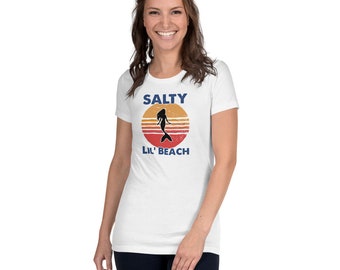 May include: White t-shirt with a vintage-style graphic of a mermaid in a sunset with the text "Salty Lil' Beach".