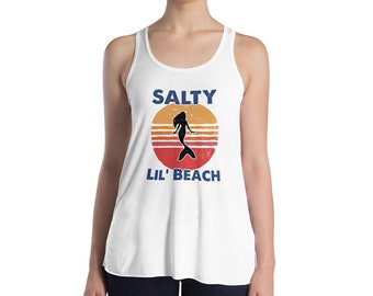 May include: White tank top with a retro sunset graphic and a mermaid silhouette. The text "Salty Lil' Beach" is printed in blue below the graphic.