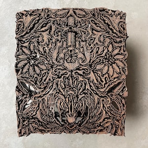 Könnte beinhalten: Ein quadratischer, hölzerner Batik-Druckblock mit einem detaillierten, komplizierten Design aus floralen und Blattmotiven. Der Block ist aus dunkelbraunem Holz gefertigt und hat ein erhabenes Design.