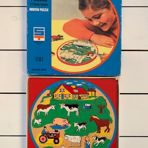 Puede incluir: Un rompecabezas de animales de granja de madera para niños de 2 a 6 años. El rompecabezas presenta una tabla circular con una escena de granja y varias piezas de animales para colocar en los lugares correctos. La caja es azul y presenta a una niña jugando con el rompecabezas.