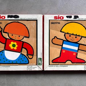 May include: Two Sio Primo wooden plywood puzzles in original boxes. The left puzzle features a figure with an orange hat, red shirt with a yellow flower, and blue skirt. The right puzzle shows a figure with a yellow hat, blue and white shirt, and red pants.