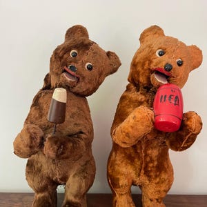 Peut inclure: Deux ours en peluche vintage de couleur marron avec des visages peints. Un ours tient un cylindre rouge avec le mot "MED" dessus. L'autre ours tient un cornet de glace brun et blanc.
