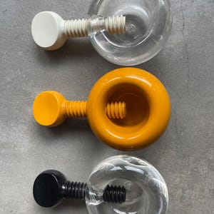 May include: Three nutcrackers shaped like a screw. The first is white with a clear plastic nut, the second is yellow with a yellow nut, and the third is black with a clear plastic nut.