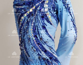 May include: A light blue figure skating dress with long sleeves and a white ombre skirt. The dress is decorated with blue and silver rhinestones and sequins.
