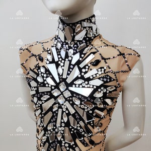May include: A black leotard with a high neckline and short sleeves. The leotard is covered in rhinestones and mirrored pieces, creating a sparkling and eye-catching design.
