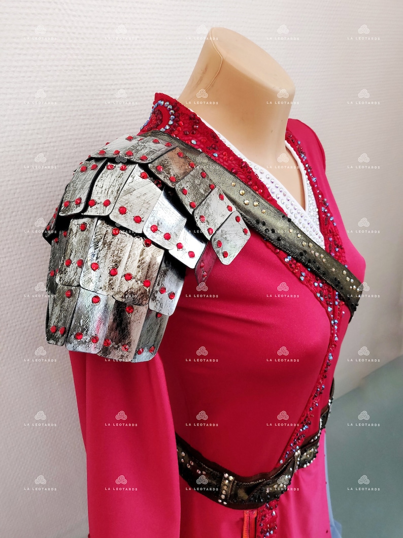 May include: A red dress with a silver and black armor-like shoulder piece decorated with red jewels. The dress has a black belt with silver accents and a white and blue trim.