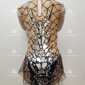 May include: A black and silver leotard with a mesh design and rhinestones. The leotard has a high neckline and a skirt.
