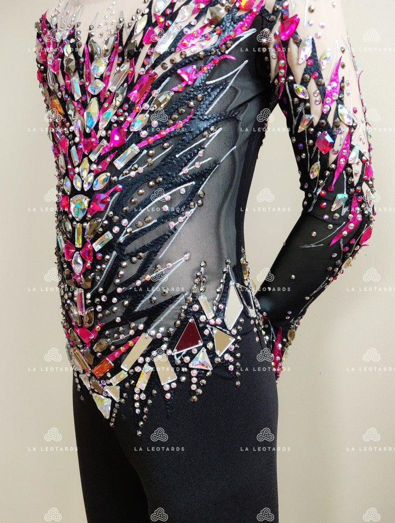 May include: Black leotard with long sleeves and a mesh bodice. The bodice is decorated with rhinestones and pink and silver accents. The leotard has a black skirt.