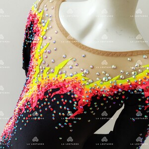 Puede incluir: Leotardo negro con un dise&ntilde;o de llama colorido. El dise&ntilde;o est&aacute; hecho de pedrer&iacute;a en tonos rojos, naranjas, amarillos y verdes. El leotardo tiene un escote redondo y mangas cortas.