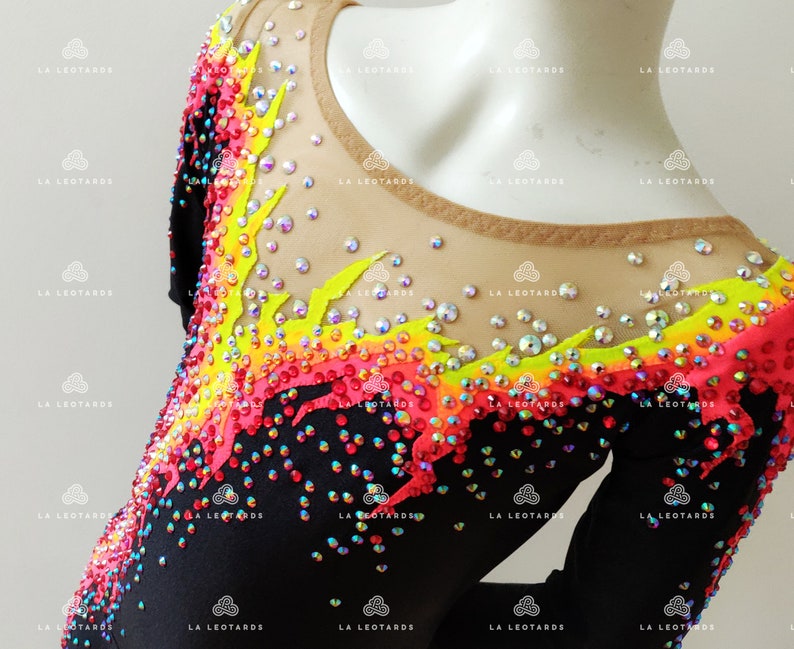 Puede incluir: Leotardo negro con un dise&ntilde;o de llama colorido. El dise&ntilde;o est&aacute; hecho de pedrer&iacute;a en tonos rojos, naranjas, amarillos y verdes. El leotardo tiene un escote redondo y mangas cortas.