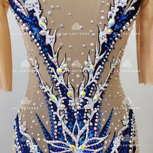 Pu&ograve; includere: Un body color carne con un designo floreale blu e bianco. Il body &egrave; ricoperto di strass e ha una sovrapposizione in rete. Il body &egrave; per ginnastica o danza.