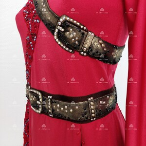 May include: A red dance costume with a gold and black jeweled belt and a gold and black jeweled shoulder strap.
