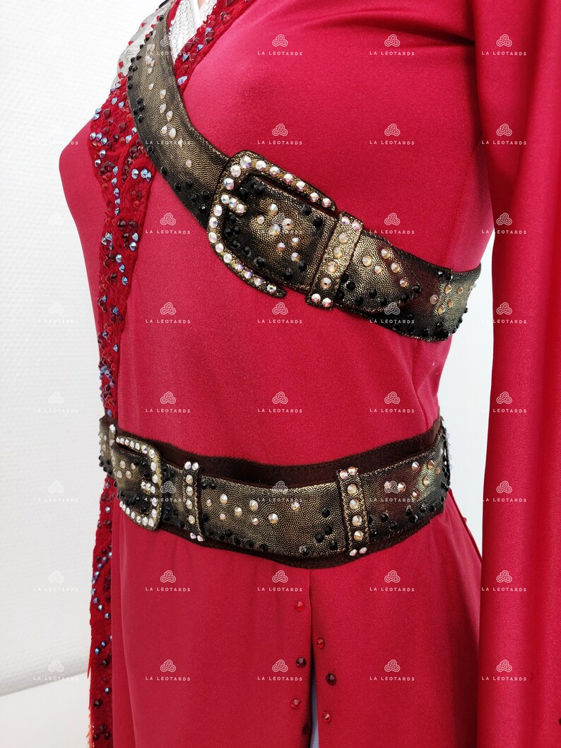 May include: A red dance costume with a gold and black jeweled belt and a gold and black jeweled shoulder strap.