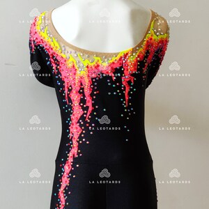 Puede incluir: Leotardo negro con un dise&ntilde;o rosa, amarillo y azul. El leotardo est&aacute; cubierto de pedrer&iacute;a y tiene un escote redondo.