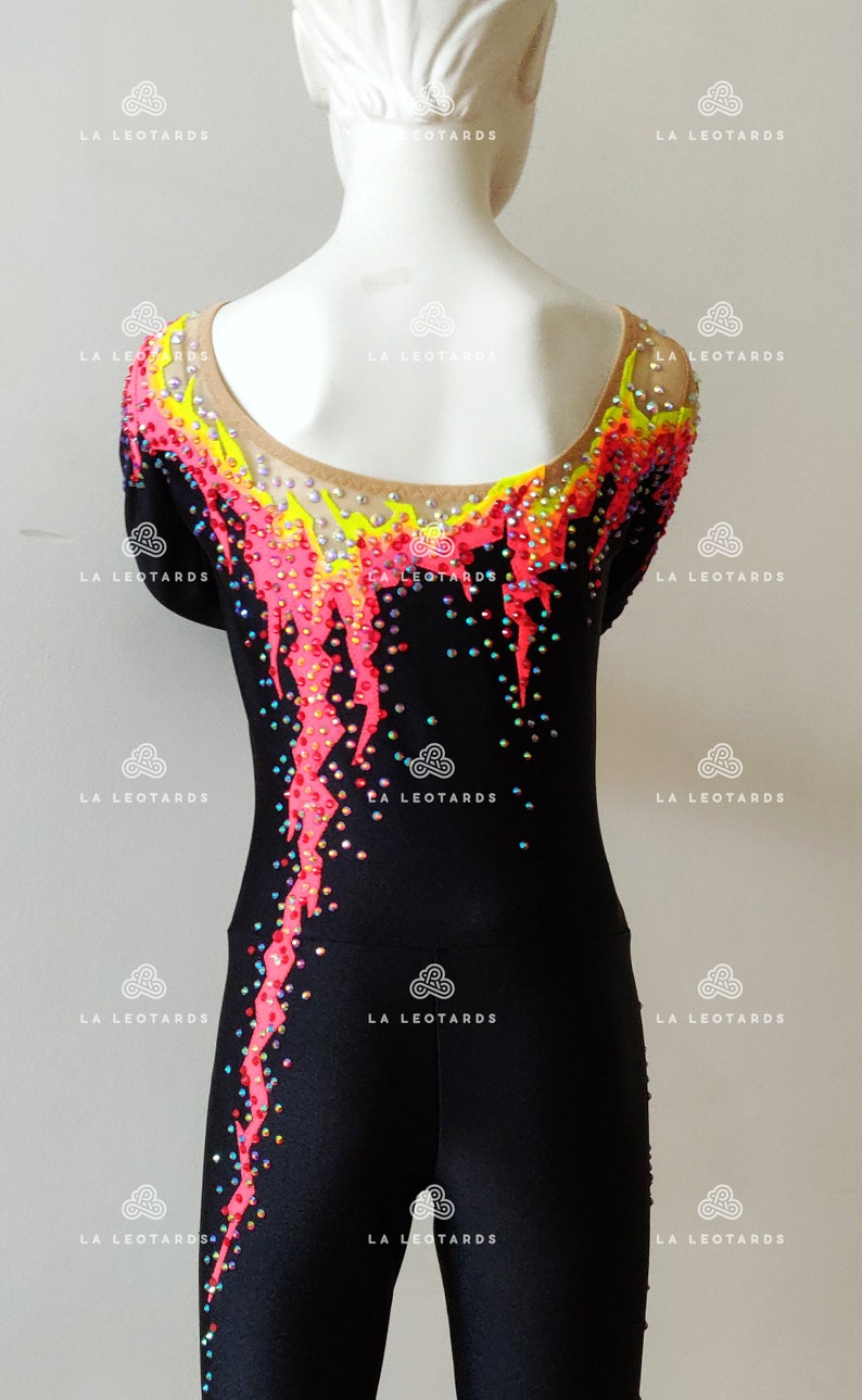 Puede incluir: Leotardo negro con un dise&ntilde;o rosa, amarillo y azul. El leotardo est&aacute; cubierto de pedrer&iacute;a y tiene un escote redondo.