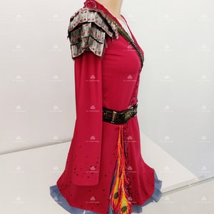May include: A red figure skating dress with long sleeves, a silver shoulder piece, a brown belt, and a colorful feather design on the skirt.