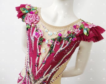May include: A red leotard with a floral design featuring pink, green, and clear rhinestones. The leotard has a scoop neck and short sleeves with ruffles.