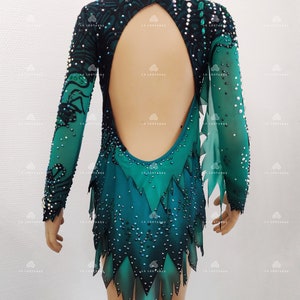 May include: A teal and black leotard with long sleeves and an open back. The leotard is embellished with sequins and features a high neckline and a unique skirt design with pointed edges. The sleeves are sheer.
