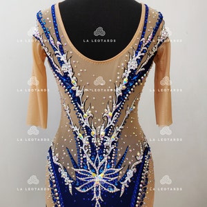 Pu&ograve; includere: Un body color carne con maniche lunghe e un design blu e bianco. Il body &egrave; ricoperto di strass e ha una profonda scollatura a V.