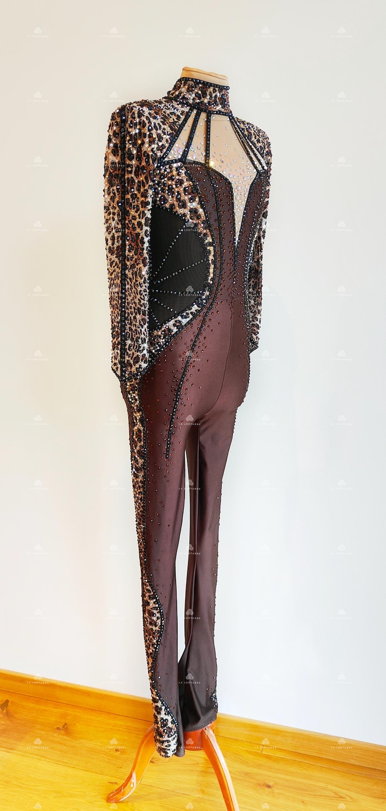 May include: A brown and black jumpsuit with a leopard print design. The jumpsuit has a high neck and long sleeves. The back of the jumpsuit features a mesh panel with a geometric design.