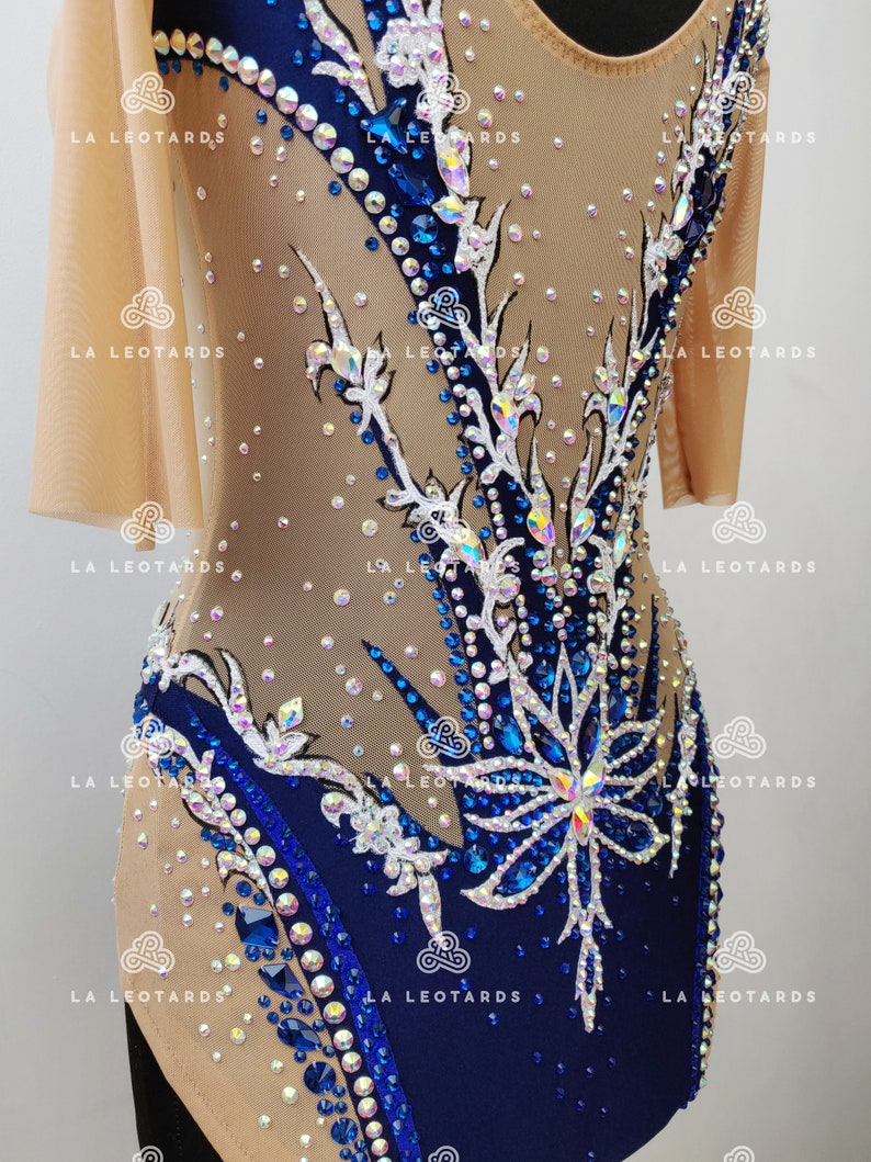 Pu&ograve; includere: Un body blu e nudo con un design floreale e strass. Il body ha maniche corte e una scollatura rotonda.