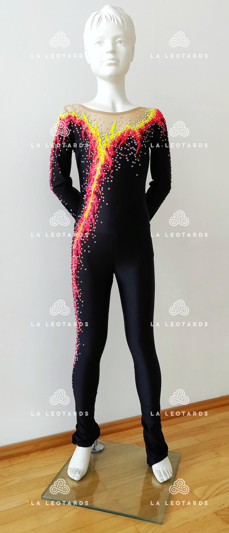 Puede incluir: Leotardo negro de manga larga con un dise&ntilde;o de llamas amarillas, rojas y rosas. El leotardo est&aacute; decorado con pedrer&iacute;a.