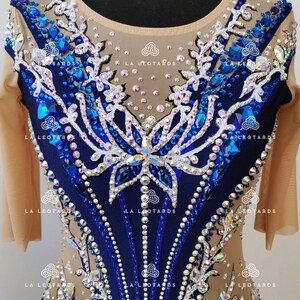 Pu&ograve; includere: Un body blu e bianco con un design a farfalla e strass. Il body ha maniche lunghe e una scollatura rotonda. Il tessuto &egrave; trasparente e il design &egrave; intricato.