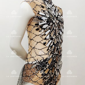 May include: A black and nude leotard with a high neckline and a design of mirrored pieces and rhinestones.