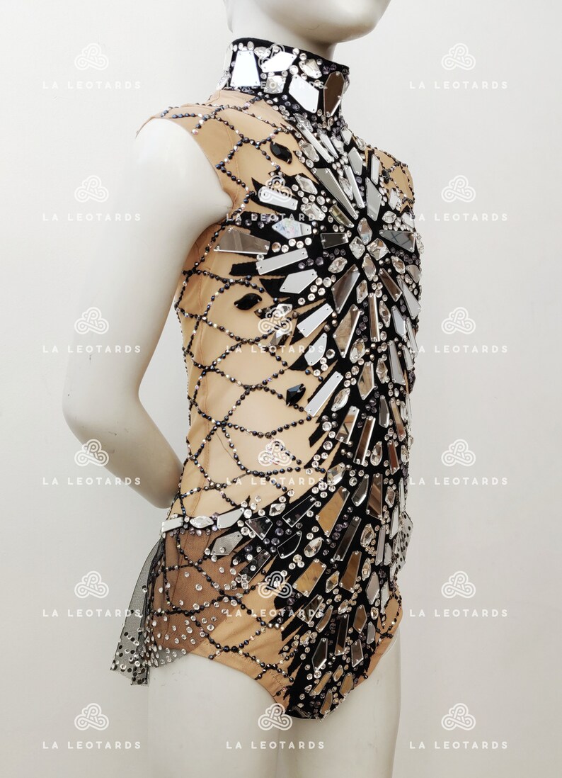 May include: A black and nude leotard with a high neckline and a design of mirrored pieces and rhinestones.