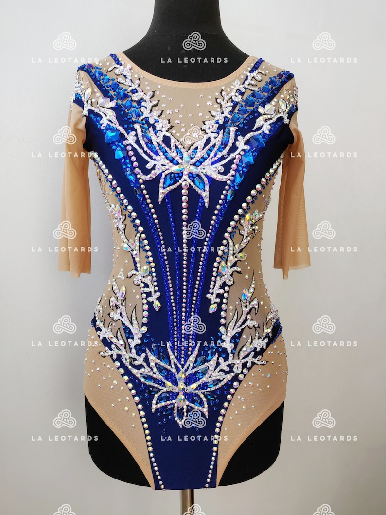 Pu&ograve; includere: Un body blu e bianco con un design floreale e strass. Il body ha maniche lunghe e una scollatura rotonda.
