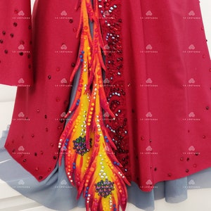 May include: A red leotard with a large, colorful, flame-like design on the side. The design is made of fabric and decorated with rhinestones.