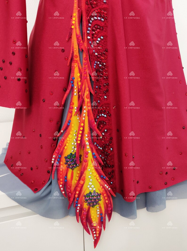May include: A red leotard with a large, colorful, flame-like design on the side. The design is made of fabric and decorated with rhinestones.