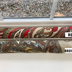 May include: Two fabric draft stoppers, one red and one brown, with a paisley pattern. The stoppers are labeled "RED" and "BROWN".
