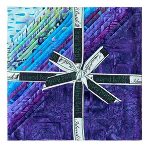 May include: A bundle of 12 purple and blue batik fabric squares tied with a green ribbon. The fabric is printed with various patterns and designs. The ribbon is labeled "Island Batik".
