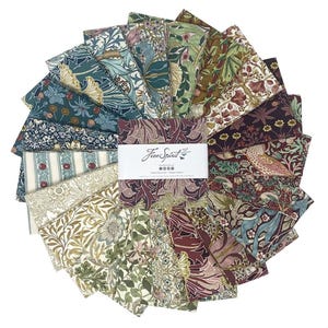 May include: A circular arrangement of fabric squares featuring diverse botanical and floral patterns in shades of blue, green, burgundy, and cream. A white paper band wraps around the centre, printed with the text Free Spirit and social icons.