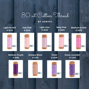 May include: A collection of 80 weight cotton thread spools in various colors, including light orchid, pale pink, light lilac, baby pink, medium orchid, medium purple, antique blush, violet, and dusty lavender. Each spool is labeled with the Aurifil brand name and a color number.