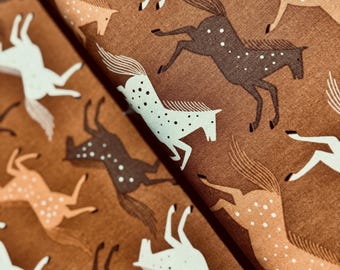 Könnte beinhalten: Ein brauner Stoff mit einem sich wiederholenden Muster aus weißen, braunen und hellbraunen Pferden, die rennen. Die Pferde sind stilisiert und haben ein einfaches Design.
