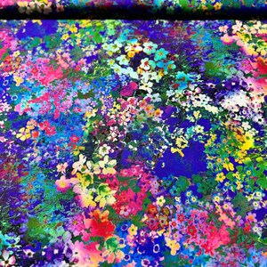 Op de afbeelding: Een levendige bloemenprintstof met een blauwe achtergrond. De stof is bedekt met een verscheidenheid aan kleurrijke bloemen, waaronder roze, gele, witte en blauwe.