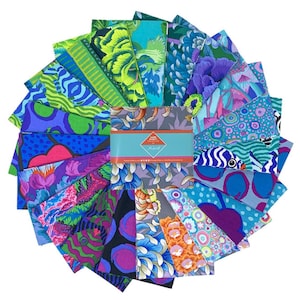 Op de afbeelding: Een verzameling kleurrijke stoffen vierkanten, gerangschikt in een cirkelvormig patroon. De stoffen hebben levendige bloemen- en abstracte ontwerpen in tinten blauw, groen, paars en oranje. Een turquoise band met tekst omwikkelt het midden van de stoffen vierkanten.