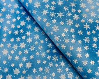 May include: A roll of blue wrapping paper with a pattern of silver snowflakes. The paper has a gradient effect, transitioning from a darker blue to a lighter shade. The snowflakes vary in size and design, creating a festive winter theme.
