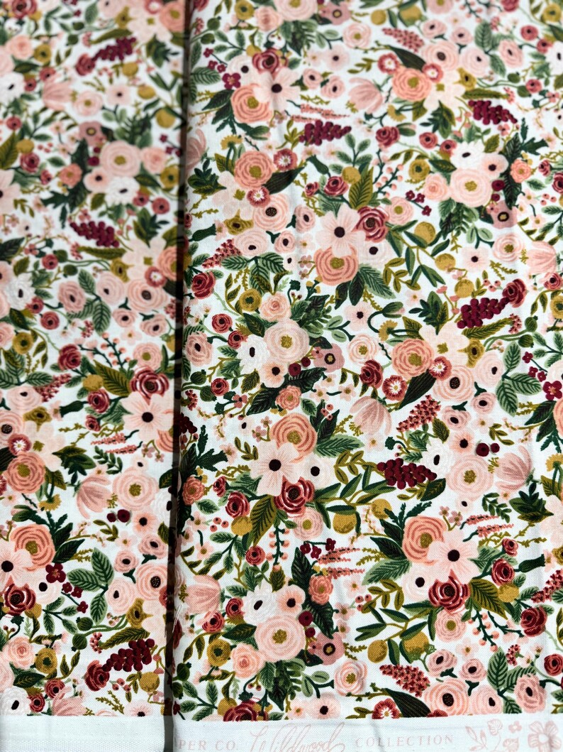May include: White fabric with a floral pattern featuring pink, red, and green flowers. The fabric has a subtle texture and a delicate design.
