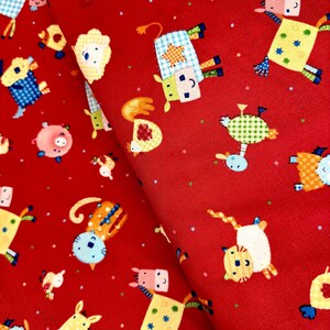Puede incluir: Tela roja con un patrón repetido de animales de dibujos animados coloridos. Los animales incluyen un caballo, una vaca, un cerdo, un gato y un pájaro. La tela tiene un patrón de lunares blancos.