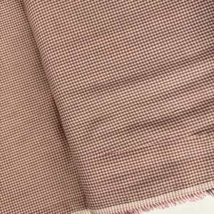 May include: A close-up of a pink and white gingham fabric with a frayed edge.