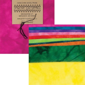 Op de afbeelding: Een set handgekleurde wolstofresten in verschillende kleuren, waaronder roze, paars, groen en geel. De stof is vastgebonden met een zwart touwtje en heeft een label met de tekst "HAND DYED WOOL FROM: PRIMITIVE GATHERINGS 850 RACINE ST. MENASHA, WI 54957 www.primitivegatherings.us (920)722-7233"