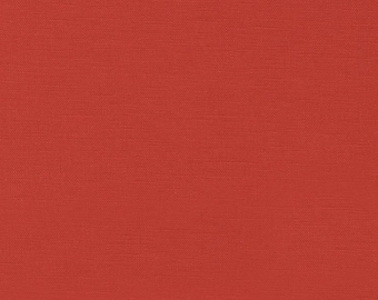 May include: A solid terracotta red fabric with a visible woven texture. A white ruler is positioned along the bottom edge, showing a measurement scale from 1 to 6 inches, indicating the scale of the fabric's weave and color consistency.